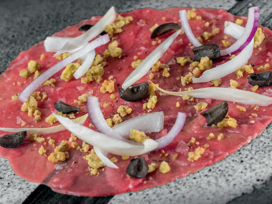 Carpaccio de bœuf accompagné d’olives, crumble de parmesan, oignons crus et piment d’Espelette