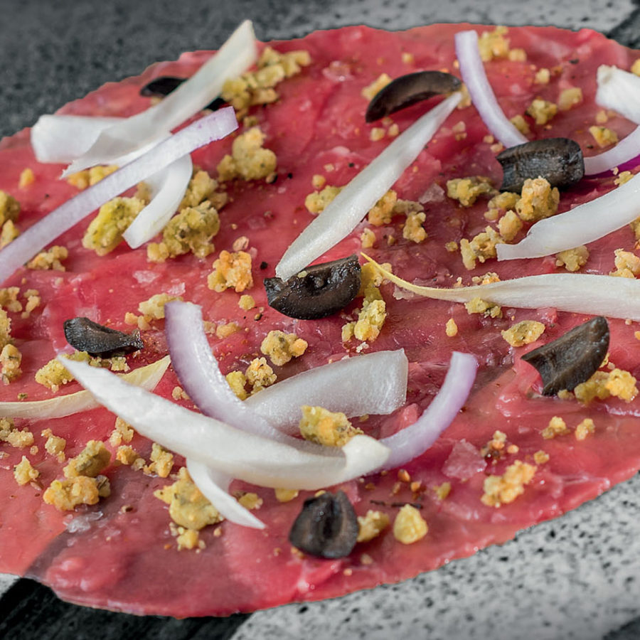 Carpaccio de bœuf accompagné d’olives, crumble de parmesan, oignons crus et piment d’Espelette